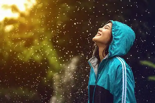 Young, beautiful woman looking happy in rain